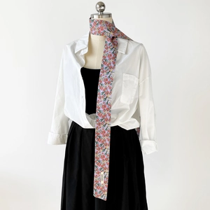 Detail eines gebundenen lila Baumwollseiden-Schals mit Blumenmuster an einer Bluse