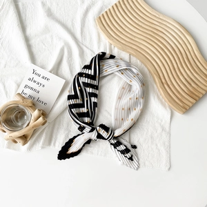 Detail of pleated silk scarf with black white stripes and golden polka dot patterns