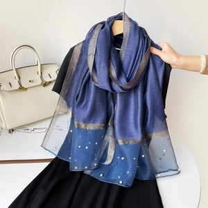 Détail d'une écharpe bleu marine nacrée avec des accents de perles blanches et tissu léger