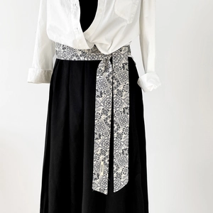 Detail eines schwarz-weißen Baumwollseidenbandes mit Paisley-Muster an der Taille geknüpft