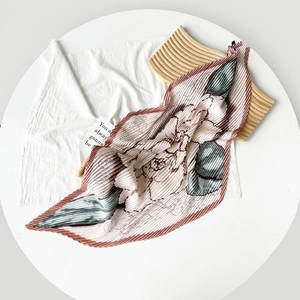 Detail of pleated satin neck scarf featuring delicate floral prints on dusty pink fabric