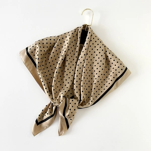 Détail d'un carré de soie avec pois noirs sur un fond de couleur champagne soyeux