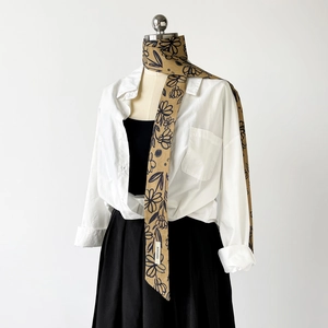 Detail eines gelben floralen Baumwollschals mit eleganten schwarzen Mustern am Hals