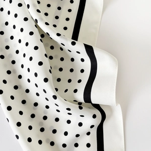 Gros plan détaillé d'un foulard en soie à pois noirs classiques et bordures à rayures noires