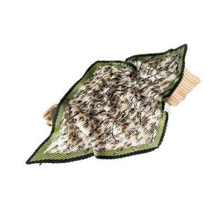 Pleated satin square scarf with floral print and zig-zag edges on a wooden base