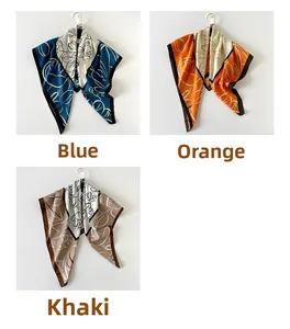 Dettaglio di foulard in raso stampati in blu, arancione e kaki con motivi floreali