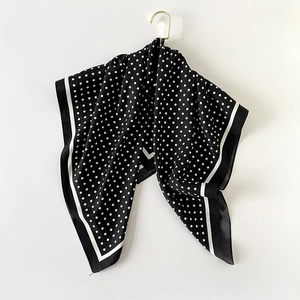 Polka dot pattern square silk scarf in black and white hanging on a gold hanger