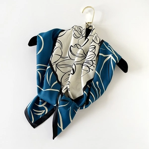 Dettaglio ravvicinato della sciarpa in raso blu e bianca con eleganti motivi floreali