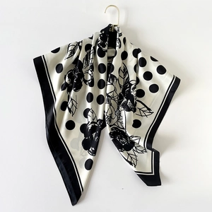 Detailed shot of black and white polka dot silk scarf draped on a gold hook
