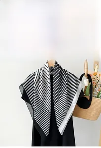 Detailed view of lightweight black and white striped silk scarf draped on a wooden hanger