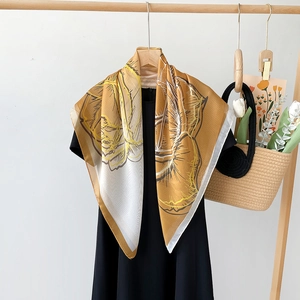Seidiges Seidenschal-Viereck mit Blumenprint in Senfgelb auf schwarzem Kleid hängend
