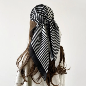 Elegant thin black and white striped silk scarf tied as a headscarf for summer fashion