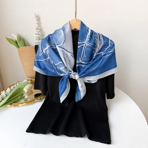 Detailansicht eines blau-weißen Seidenschals mit Federdruck auf einem schwarzen Top