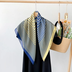Silk scarf with blue and yellow diagonal stripes on a hanger with summer accessories