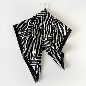 Detail of silk scarf with zebra pattern and smooth satin finish hanging on gold hook