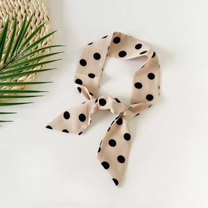 Close-up of beige polka dot silk scarf with decorative green leaves on a white background