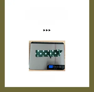 Detailed view of lightweight green polka dot silk scarf on a digital scale for weight display