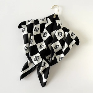 Dettaglio foulard in seta a scacchi con motivo monogramma su gruccia dorata di lusso