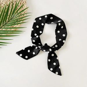 Polka dot skinny silk scarf styled in a bow with summer straw mat and green leaf decor