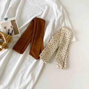Detailed texture of brown and beige polka dot silk scarves on a clean white t-shirt