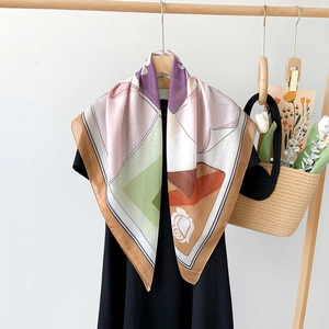 Close-up of elegant square silk scarf with geometric blocks and white rose floral print