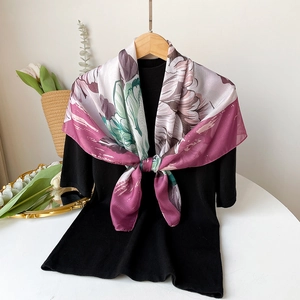 Detailed close-up of a floral silk scarf styled with a knot on a black sweater