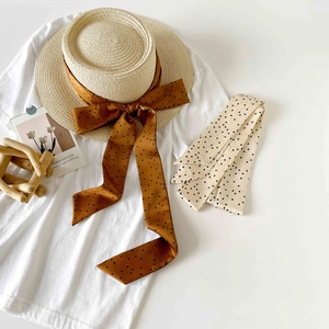Close-up of flat top straw hat with polka dot ribbons for a chic summer vacation look