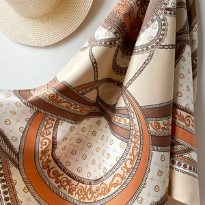 Détail d'un élégant foulard carré en satin avec motifs chaînes vintage et logos déco