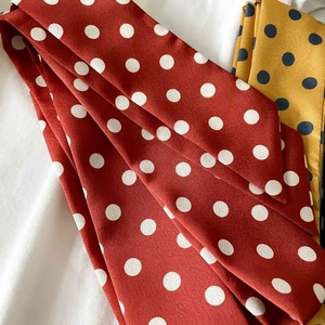Close-up of red and yellow polka dot skinny scarves with silky satin texture detail