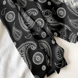 Close-up of black paisley pattern silk scarf texture showing fine fabric detail