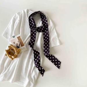 Close-up of navy polka dot skinny scarf tied on a white shirt in a minimalist style