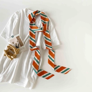 Detailed view of long striped satin scarf tied on white shirt collar for style