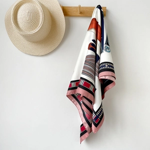 Détail d'un carré de soie avec imprimé chaîne de luxe accroché à un crochet en bois