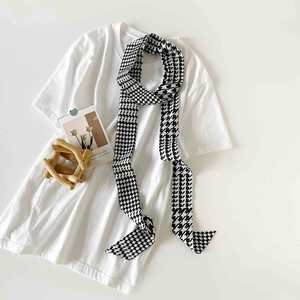 Close-up of classic black and white houndstooth skinny silk scarf on minimalist background