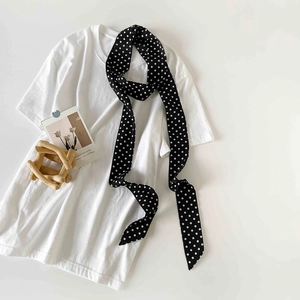 Detailed view of polka dot silk scarf tied on a white shirt neck for a chic look