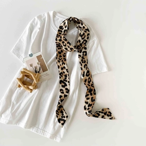 Flat lay of a leopard print satin skinny scarf paired with a white casual t-shirt