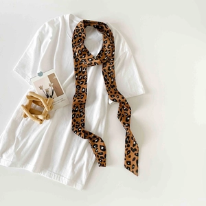 Detail of leopard print skinny silk scarf tied on a white tee with twilly styling