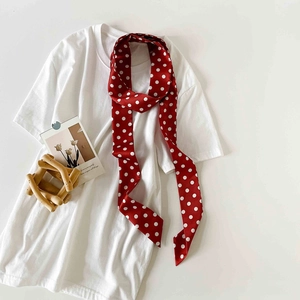 Close-up of red polka dot silk scarf tied on white T-shirt with lifestyle props