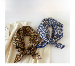 Detail of two lightweight cotton scarves with geometric patterns on a knit sweater