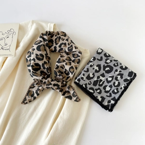 Detailed view of leopard print cotton scarf with lace trim on a beige knit sweater