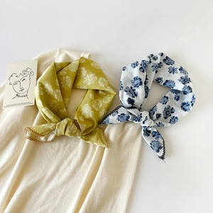 Close-up of floral print cotton square scarves with scalloped edges on knit fabric