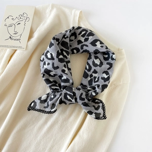 Detail of leopard print cotton scarf with black lace trim on a knit background