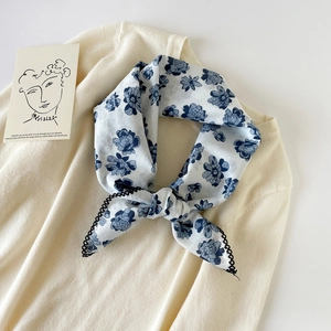 Detail of floral cotton neckerchief with black crochet lace trim on a knit sweater