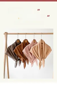 Detail of four earth-toned chiffon hijabs in brown and beige on wooden hangers