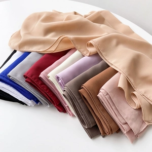Multiple colorful chiffon hijab scarves neatly stacked showing soft texture and drapes