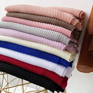 Macro view of plissé pleated pearl chiffon scarves in various vibrant colors on a gold rack