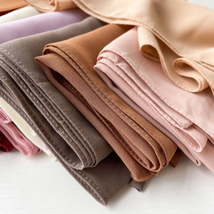 Macro shot of chiffon hijabs in Morandi tones with neat stitched edges on wood