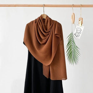 Detailed texture of brown pleated chiffon scarf displayed on a black sleeveless dress