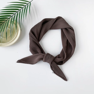 Detail of a brown plissé chiffon scarf with fine pleats on a ceramic plate