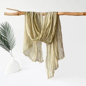 Detail of olive green crinkled jersey scarf draped over a wooden branch